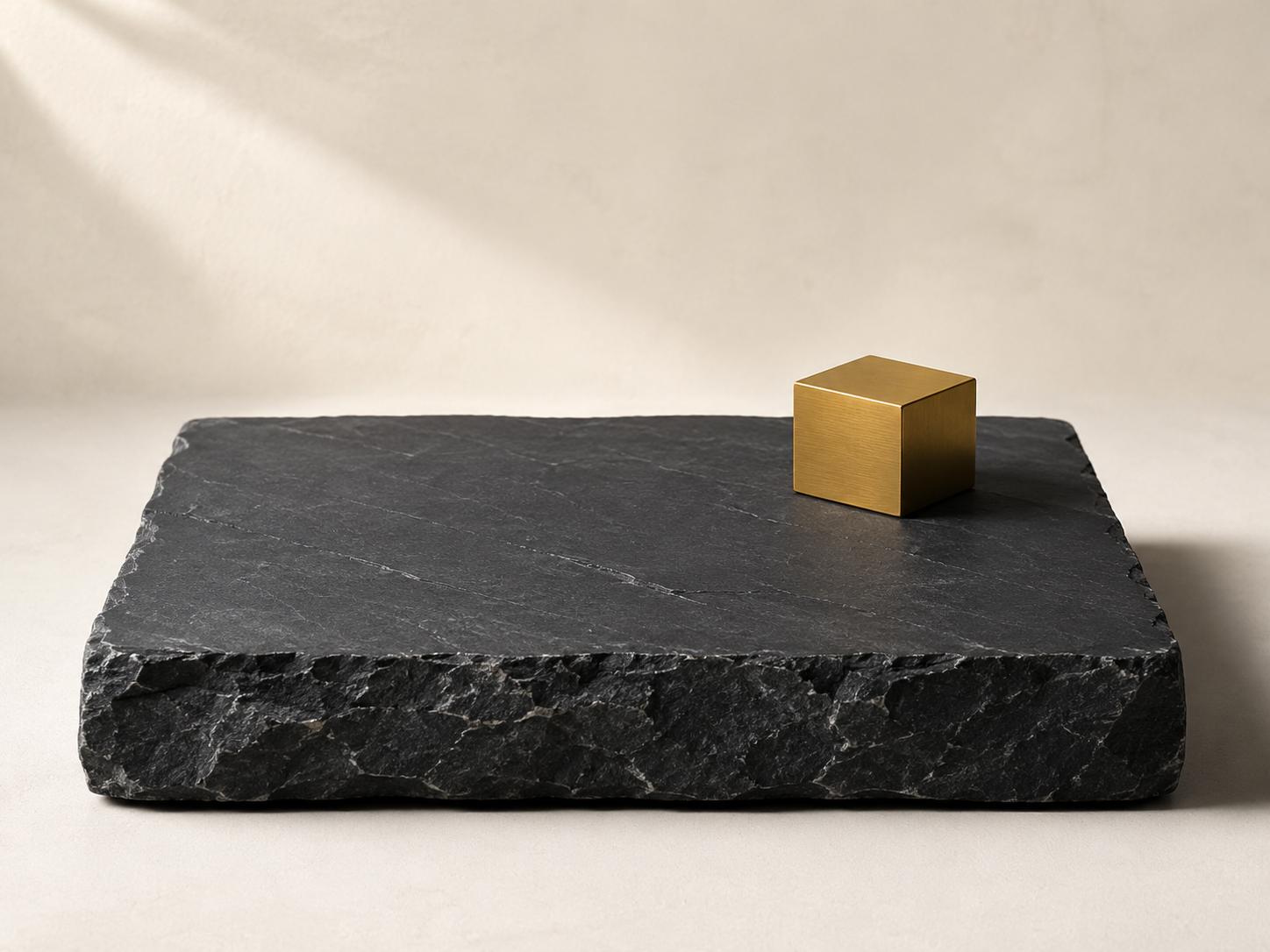A single broad slab of dark slate resting solidly on a pale surface, lit from the side — a visual metaphor for a clean financial foundation